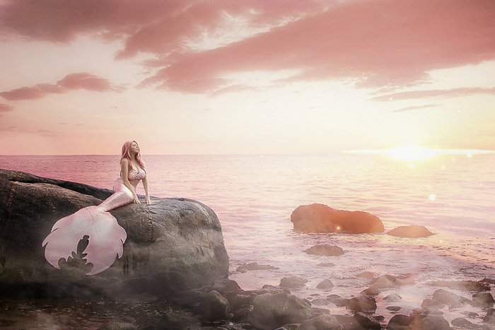 Dreamy self portrait boudoir photography of a female model posing in a mermaid tail by the sea