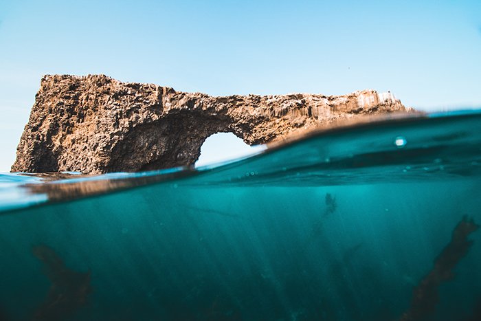 Подводная фотография скалы в море наполовину сверху, наполовину снизу