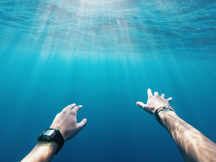 Крутая подводная фотография вытянутых рук пловца