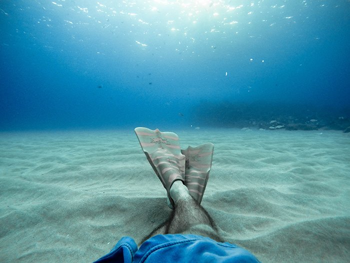 Крутой подводный портрет пловца со скрещенными ногами