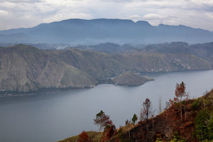 Крутые горы, окружающие озеро, кальдера вулкана Тоба. -фотография вулкана и лавы