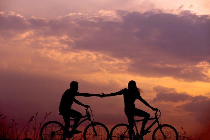 силуэт пары на велосипедах на закате в летнее время