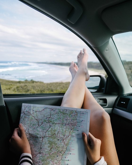 Креативный летний портрет девушки в машине, читающей карту