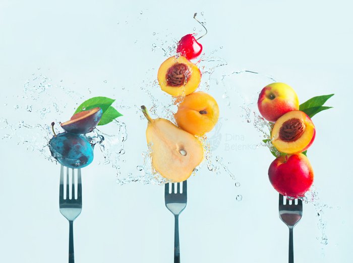 Крутой натюрморт с изображением фруктов на вилке в окружении брызг воды