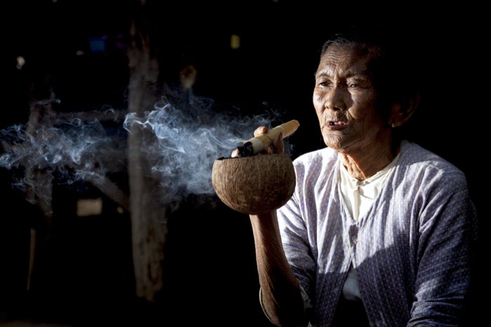 портрет пожилой женщины, курящей в низком ключе, снятый с использованием вспышки слева от камеры