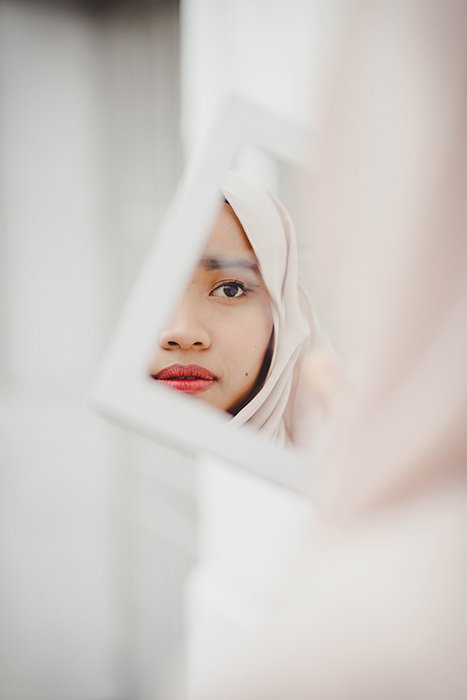 Поразительный портрет красивой модели, позирующей перед зеркалом для фотосессии с макияжем