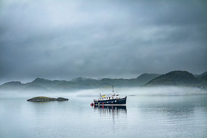 Лодка в туманном морском пейзаже на закате
