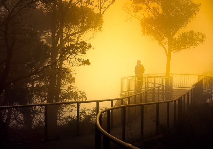 Человек на мосту в туманном пейзаже на закате