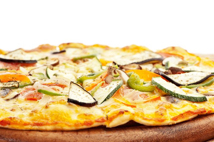 Крупный план свежеприготовленной вегетарианской пиццы, снятой с одним софтбоксом прямо за объектом съемки. 