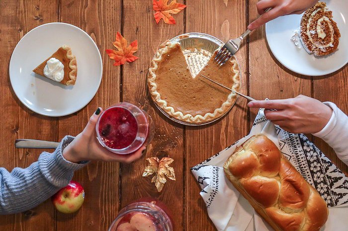 A thanksgiving photography flatlay featuring food and drinks on the wooden table