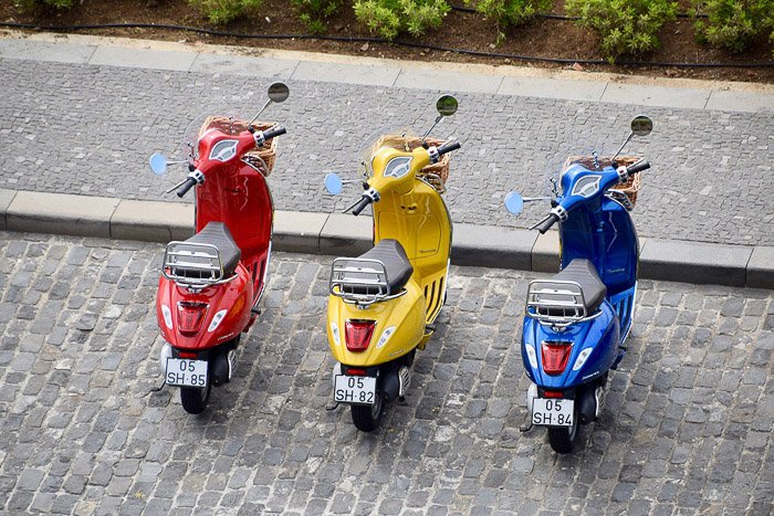 Аэрофотография красных, желтых и синих скутеров, припаркованных рядом друг с другом - триадическая цветовая схема