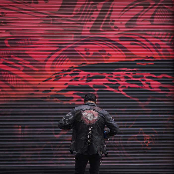 Атмосферный портрет мужской модели, угрюмо позирующей у расписанной граффити стены