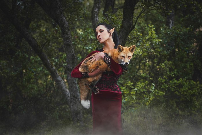 A fantasy themed portrait of a female model in elf costume holding a fox 