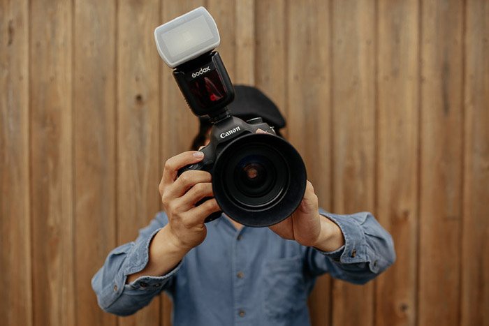 Фотограф держит камеру dslr с прикрепленным рассеивателем вспышки