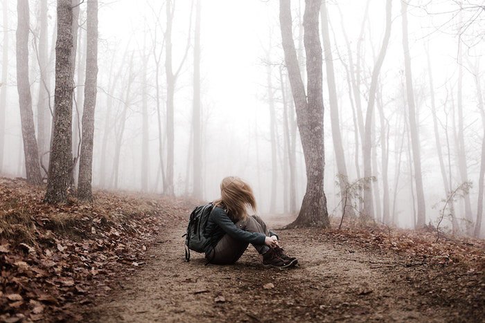 Атмосферный портрет девушки, сидящей в лесу, отредактированный с помощью функции Lightroom dehaze