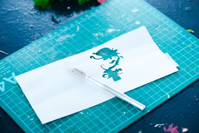 вырезанный силуэт цветка в листе бумаги на коврике для резки