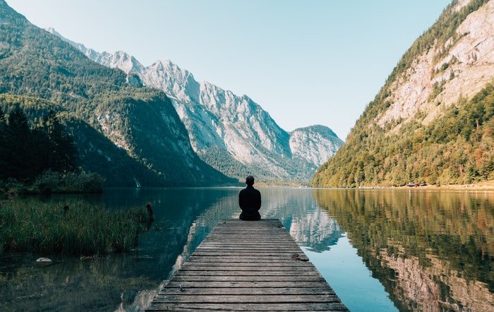 одинокая фигура, сидящая на деревянном пирсе у озера, использование динамического диапазона в фотографии