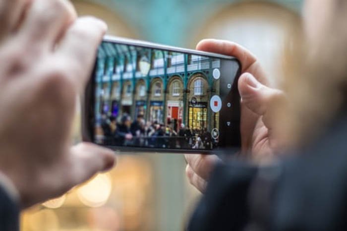 человек делает уличную фотографию со смартфона - iphone vs android камера