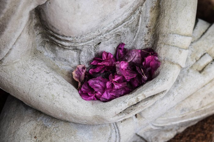 фиолетовые цветы, собранные в руках каменной статуи - символизм в фотографии