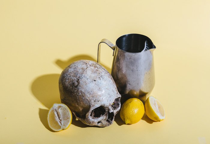 натюрморт с черепом, лимонами и вазой на бледно-желтом фоне - символизм в фотографии