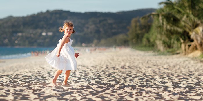 маленькая девочка бежит по пляжу, ее действия застыли в движении
