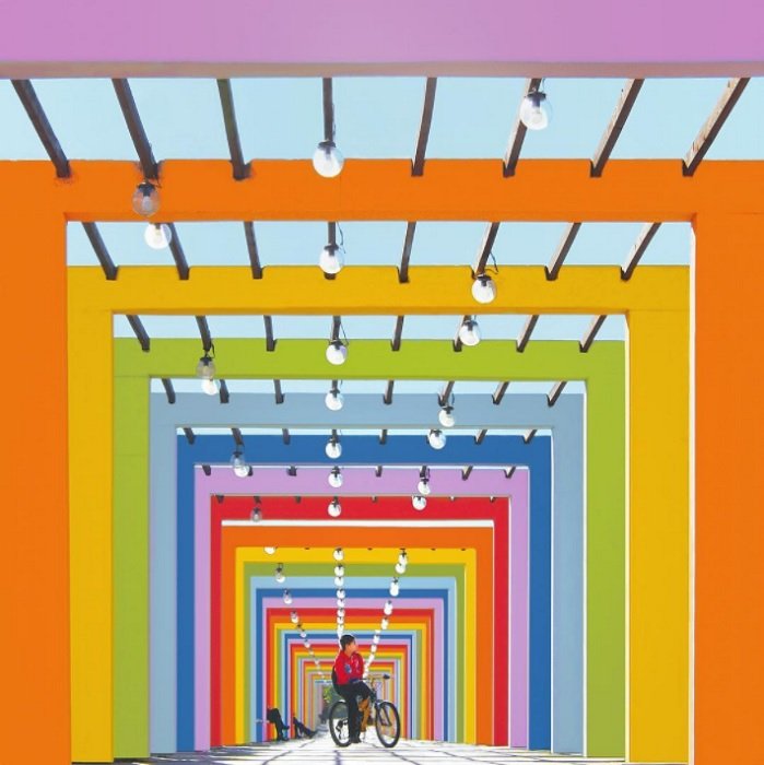Велосипедист на дорожке с разноцветными строительными лесами как пример геометрической фотографии