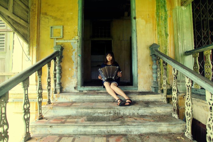 Фотография девушки, играющей на аккордеоне на лестнице заброшенного дома