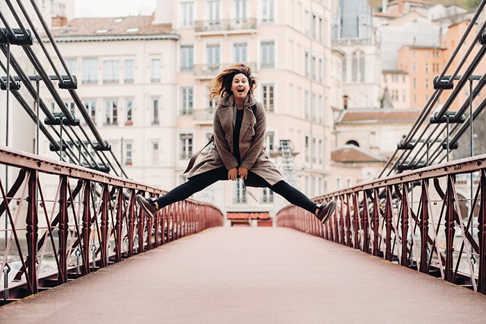 Девушка прыгает по симметричному мосту.