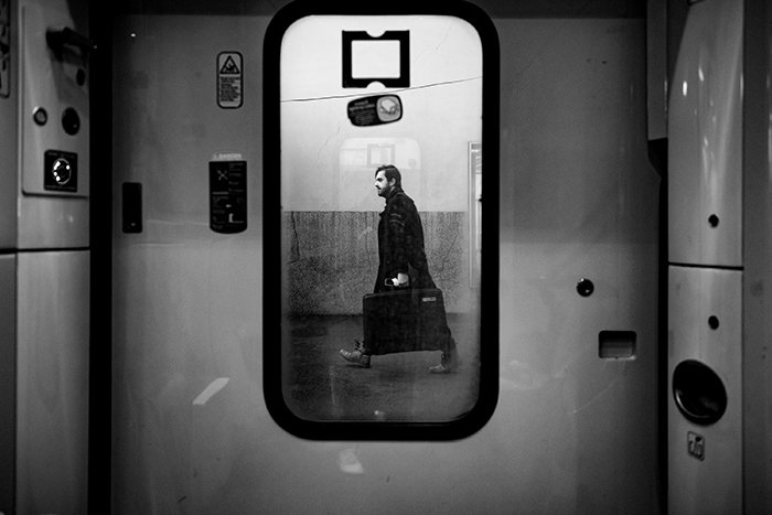 Фотография мужчины, идущего с чемоданом, отражающимся в зеркале
