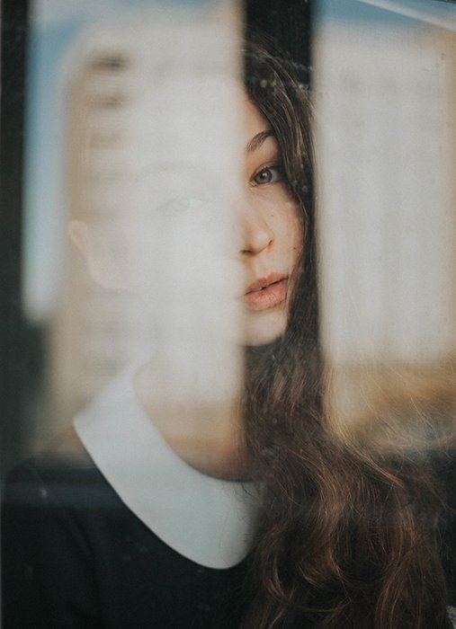Портретная фотография женщины, снятая через окно