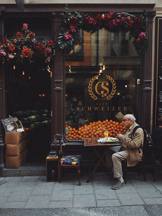 Фотография пожилого мужчины, завтракающего в небольшом кафе