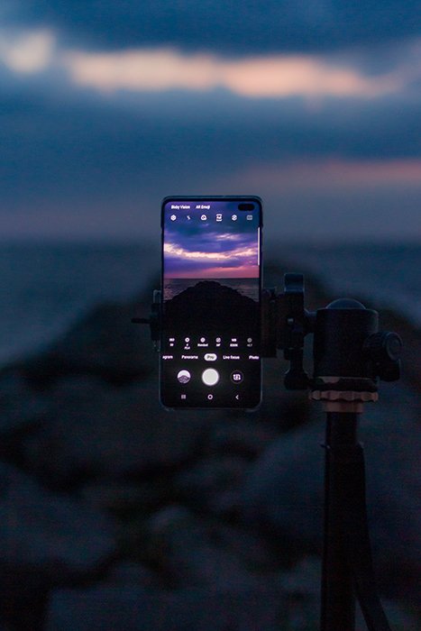 смартфон на штативе снимает великолепный закат
