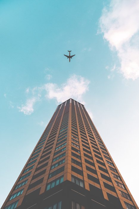 Фотография самолета и высокого здания с перспективы, обращенной вверх