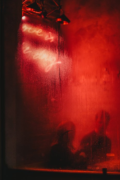 Фотография бара с красным светом, отражающимся на окне