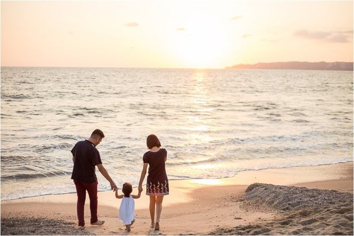 милый семейный портрет родителей, держащих за руку маленькую девочку на пляже