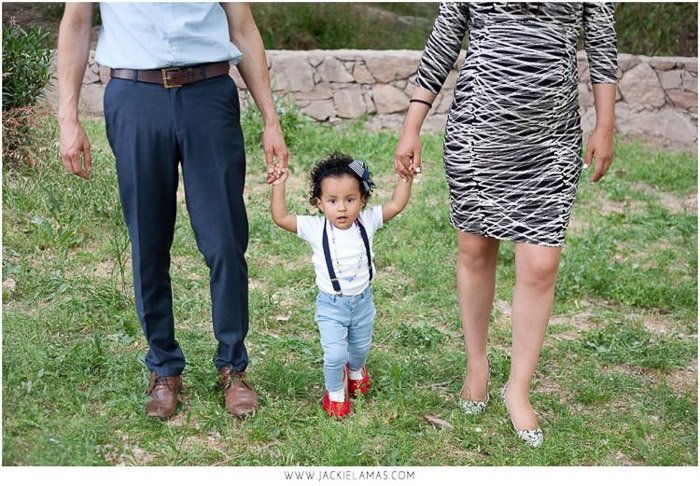 милый семейный портрет родителей, держащих маленькую девочку за руку на улице