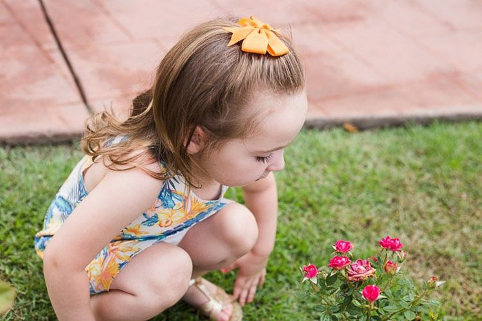 lifestyle портрет маленькой девочки, приседающей на траву