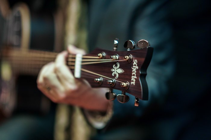 Фотография крупным планом рук мужчины, держащего гитару