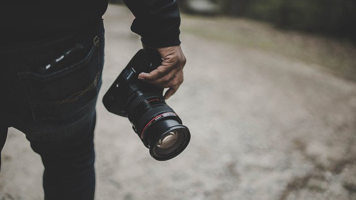 фотограф держит самую дешевую полнокадровую зеркальную камеру рядом с собой