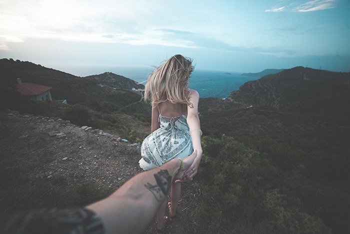 Женщина идет по роскошному пейзажу, держа своего партнера за руку