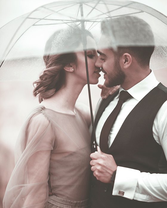Романтический снимок молодой пары, позирующей под зонтом