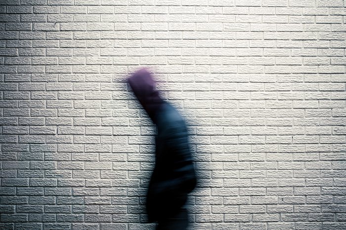 Человек, идущий перед стеной, снятый с размытием движения
