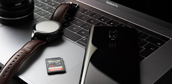 Наручные часы, мобильный телефон и карта памяти на открытом ноутбуке