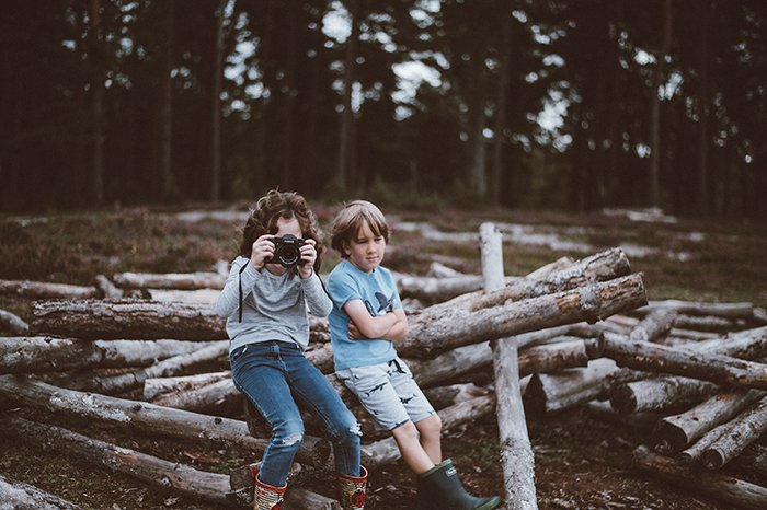 Фотография детей, сидящих на бревнах и фотографирующихся на камеру