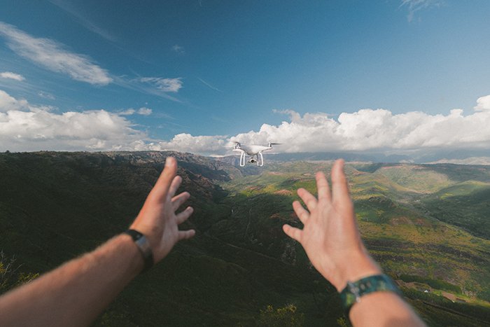 Фотография рук, отпускающих летящий дрон