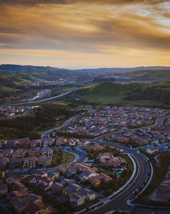 Фотография города с холмами на закате с дрона