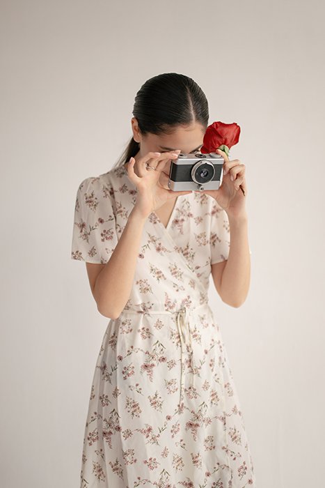 девушка в цветочном платье фотографируется на пленочную камеру