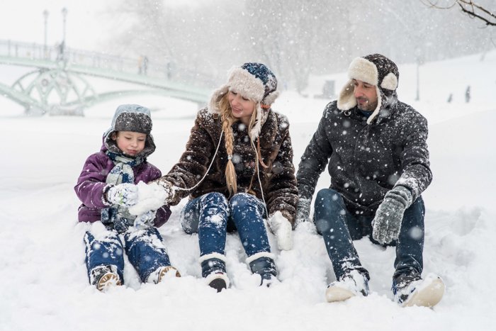 семья из трех человек сидит на снегу
