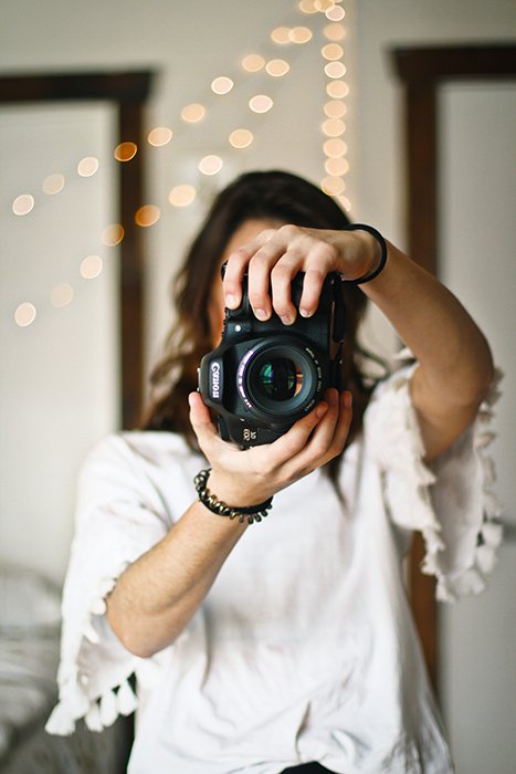 женщина-фотограф держит в руках зеркальный фотоаппарат canon