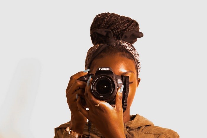 Женщина держит фотоаппарат с зум-объективом